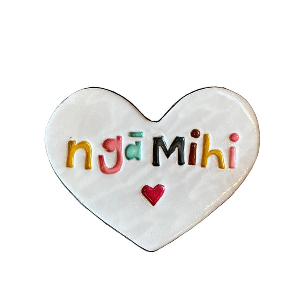 Heart-shaped ceramic tile with 'ngá Mihi' in colorful letters on a textured surface