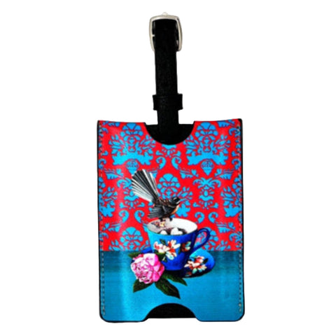 Luggage tag with a colorful design featuring a teacup and flowers on a red and blue patterned background.