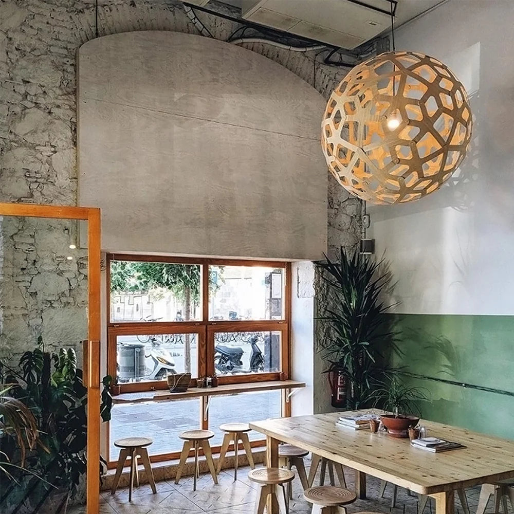 David Trubridge Coral pendant light styled above a timber table in a warm café interior