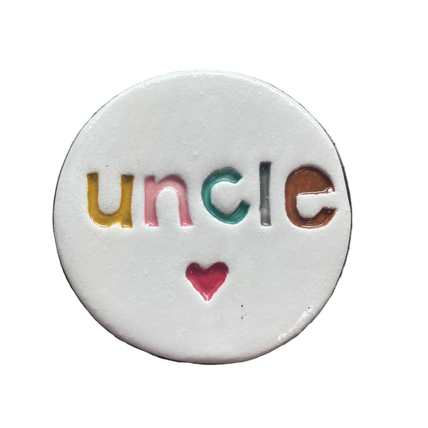 Round ceramic tile with 'uncle' and a heart on a textured gray background